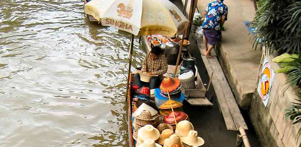 Vendors selling hats and traditional goods from canal boat - representing authentic budget-friendly market experience