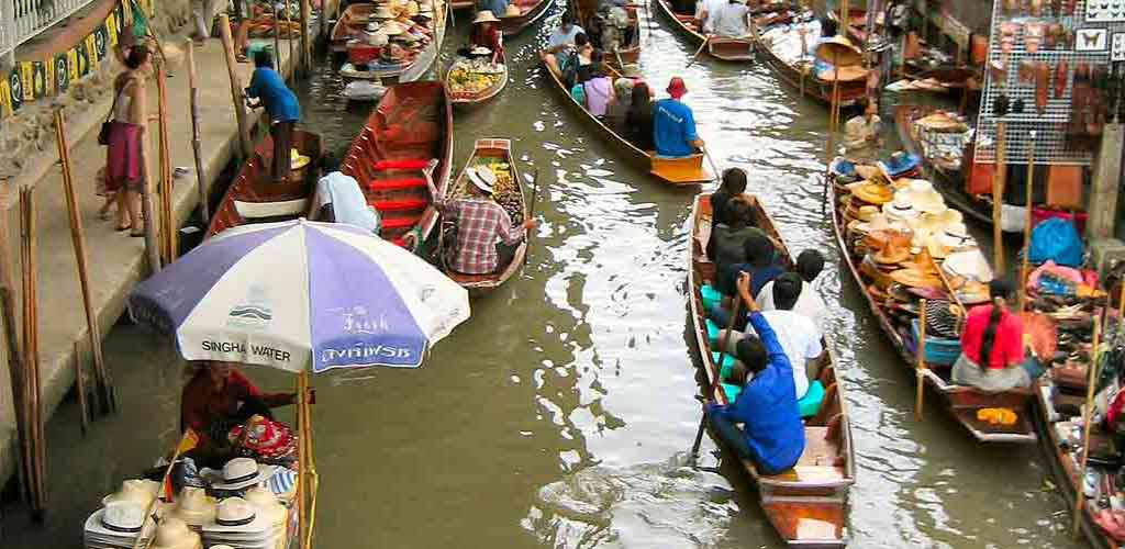 Bustling floating market in Bangkok with vendors in boats - representing exclusive VIP tour experiences